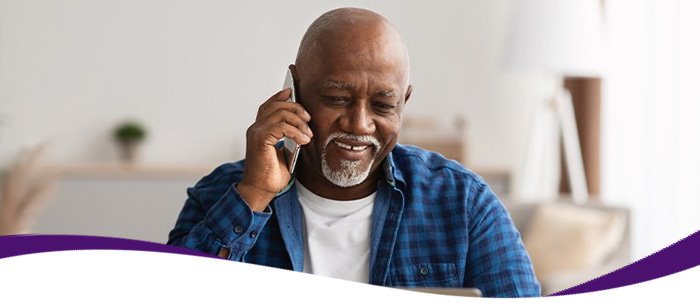 Older man renewing his Medicare insurance plan online while on the phone with a Medicare insurance specialist